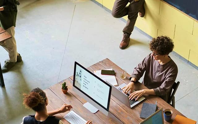 Two people work on computers at the table